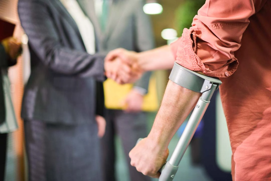 Man on crutches shaking hands.